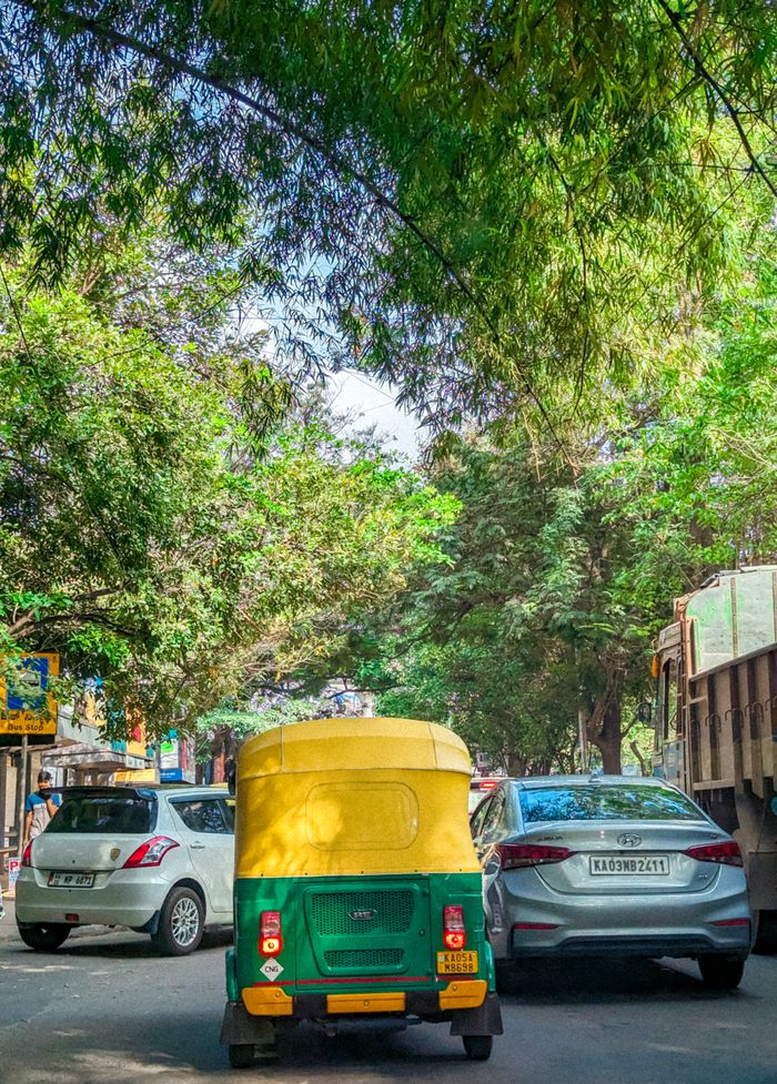 Crafting Captivating Headlines: Your awesome post title goes here Vibrant street scene featuring an auto rickshaw and cars under lush green trees.