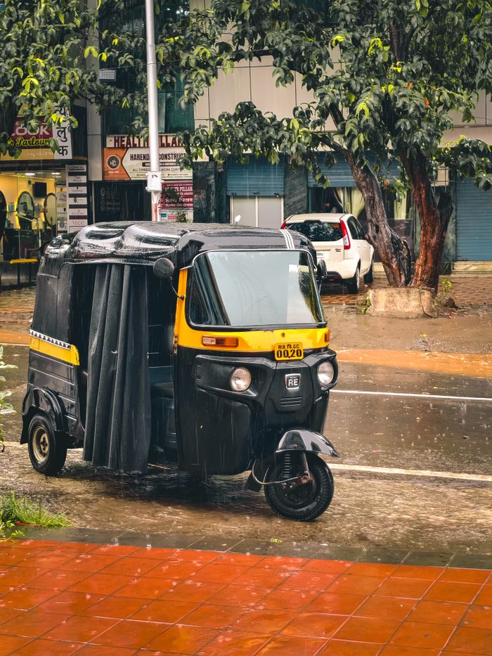 Mastering the First Impression: Your intriguing post title goes here Auto rickshaw parked on a rainy city street, capturing urban transportation and weather.